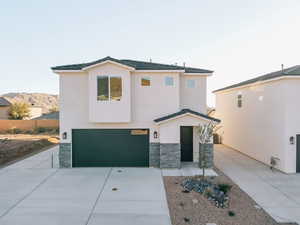 View of front of home featuring stone siding, driveway, a garage, and stucco siding
