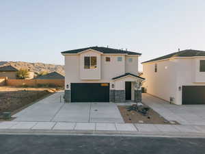 View of front of property featuring stone siding, concrete driveway, an attached garage, stucco siding, and a mountain view