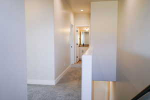 Hall featuring light colored carpet and baseboards