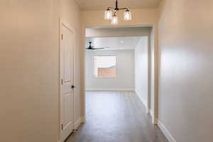 Corridor with wood finished floors and a chandelier