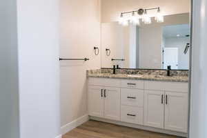 Bathroom with double vanity and light wood finished floors