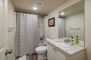 Bathroom with vanity, shower / tub combo, dark wood-type flooring, and recessed lighting