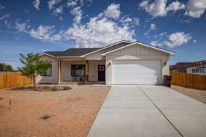 Single story home with concrete driveway, a garage, covered porch, board and batten siding, and roof with shingles