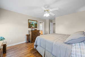 Bedroom featuring light wood-style floors, a ceiling fan, and connected bathroom