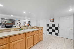 Kitchen featuring light countertops, open floor plan, light tile patterned flooring, a stone fireplace, and ceiling fan