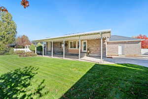 Rear view of house with brick siding, a yard, entry steps, and a porch