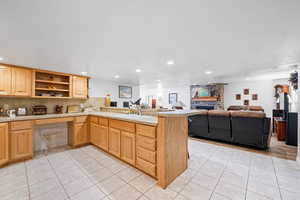 Kitchen featuring a peninsula, open floor plan, light tile patterned flooring, a fireplace, and recessed lighting