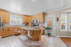 Kitchen featuring backsplash, light stone counters, appliances with stainless steel finishes, recessed lighting, and a kitchen breakfast bar