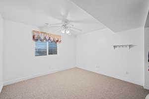 Carpeted spare room with baseboards and ceiling fan