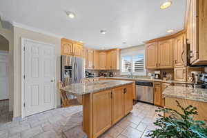 Kitchen featuring light stone counters, stainless steel appliances, stone tile flooring, a kitchen island, and a textured ceiling