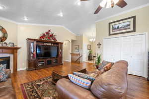 Living area featuring crown molding, lofted ceiling, hardwood / wood-style flooring, ceiling fan, and a textured ceiling