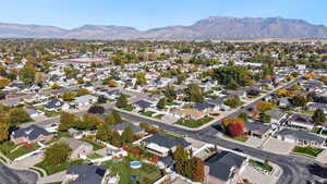 Aerial view of property and surrounding area featuring nearby suburban area and a mountain backdrop