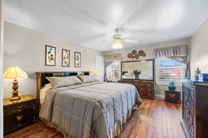 Bedroom featuring wood-type flooring, ceiling fan, and a textured ceiling