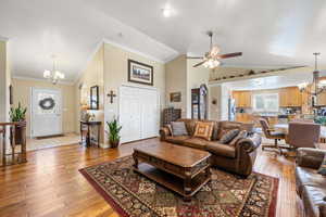 Living room with a chandelier, light wood-style flooring, crown molding, healthy amount of natural light, and ceiling fan