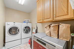 Washroom with washer and clothes dryer, cabinet space, and a textured ceiling
