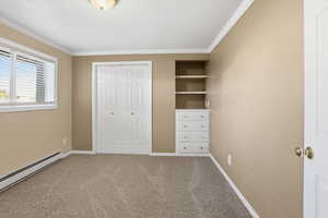 Unfurnished bedroom featuring carpet flooring, ornamental molding, a closet, and baseboard heating