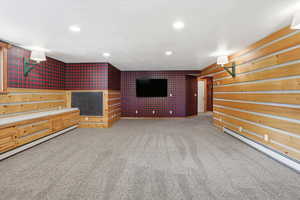 Unfurnished living room featuring light colored carpet, baseboard heating, and recessed lighting