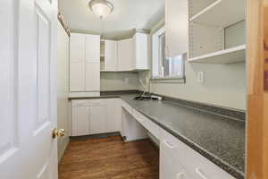 Kitchen featuring open shelves, dark countertops, dark wood-style floors, and white cabinetry