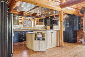 Kitchen with open shelves, light wood-style floors, log walls, pendant lighting, and beam ceiling