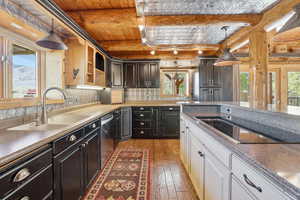 Kitchen with white cabinetry, hanging light fixtures, beam ceiling, black electric cooktop, and light wood-style flooring