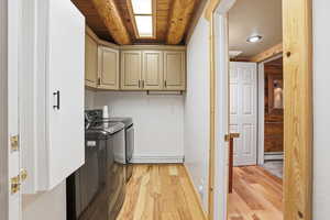 Laundry area with light wood-style flooring, cabinet space, washer and dryer, beam ceiling, and a baseboard heating unit