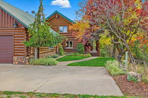 Log-style house with log siding, a front lawn, and a wooden deck