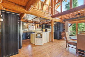 Kitchen with beam ceiling, rustic walls, light wood-type flooring, freestanding refrigerator, and open shelves