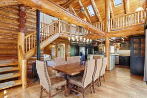 Dining area featuring high vaulted ceiling, stairway, a skylight, light wood-type flooring, and a ceiling fan
