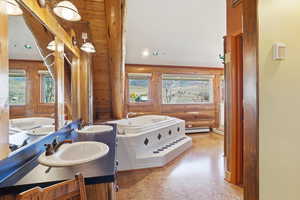 Full bath featuring a garden tub, double vanity, log walls, and a baseboard radiator