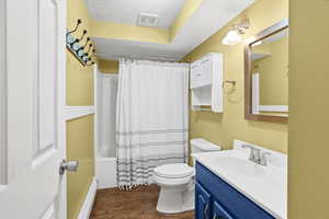 Full bathroom with shower / tub combo, vanity, a baseboard heating unit, dark wood finished floors, and a textured ceiling