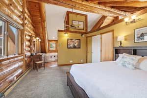 Bedroom featuring a baseboard radiator, rustic walls, high vaulted ceiling, carpet flooring, and beam ceiling