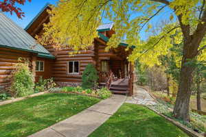 Doorway to property with log exterior, a metal roof, and a yard