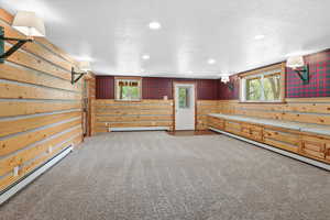 Bonus room featuring a baseboard radiator, light colored carpet, recessed lighting, a textured ceiling, and wood walls