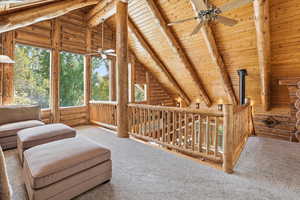 Living area with plenty of natural light, wood ceiling, an upstairs landing, rustic walls, and carpet flooring