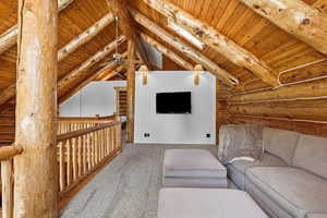 Carpeted living room with rustic walls and wood ceiling