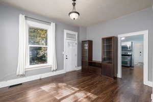 Dining area with dark wood-style flooring and baseboards