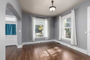 Dining area with dark wood-type flooring and arched walkways