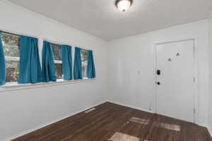 Back entrance/ possible pantry/mudroom featuring dark wood-type flooring, a textured ceiling, and crown molding