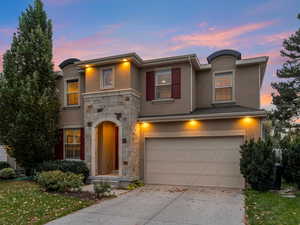 View of front of home featuring stucco siding, stone siding, a yard, concrete driveway, and a garage