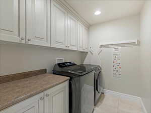 Washroom featuring cabinet space, light tile patterned floors, washing machine and clothes dryer, and recessed lighting