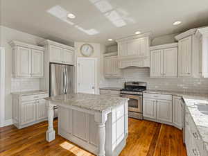 Kitchen featuring appliances with stainless steel finishes, light stone countertops, a center island, light wood-style floors, and recessed lighting