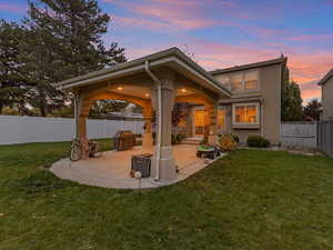 Back of property at dusk with a patio, a fenced backyard, and stucco siding