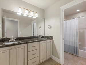Bathroom featuring shower / bathtub combination with curtain, double vanity, light tile patterned floors, and recessed lighting