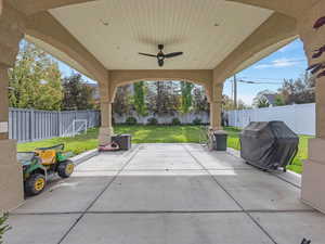 Fenced backyard with a ceiling fan, a patio area, and a grill
