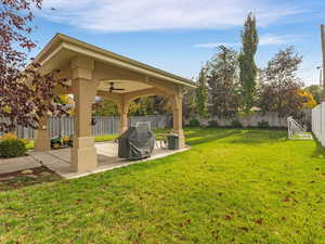 Fenced backyard featuring a patio and ceiling fan