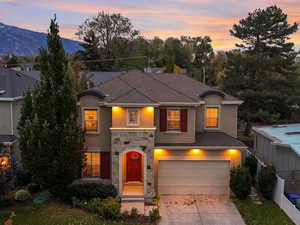 Two-story home with stucco siding, stone siding, driveway, and a garage