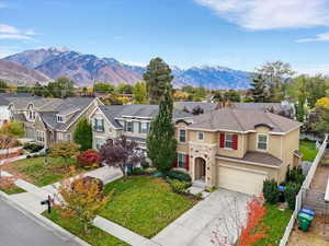 Traditional-style home featuring stucco siding, a residential view, driveway, an attached garage, and a mountain view
