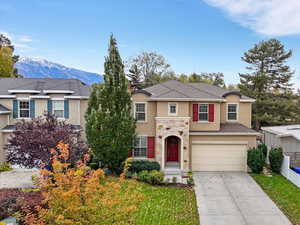 View of front of house featuring stucco siding, stone siding, driveway, a garage, and a mountain view