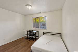 Bedroom with dark wood-type flooring and a textured ceiling