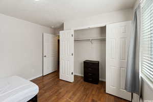 Bedroom with dark wood-type flooring, a closet, and a textured ceiling